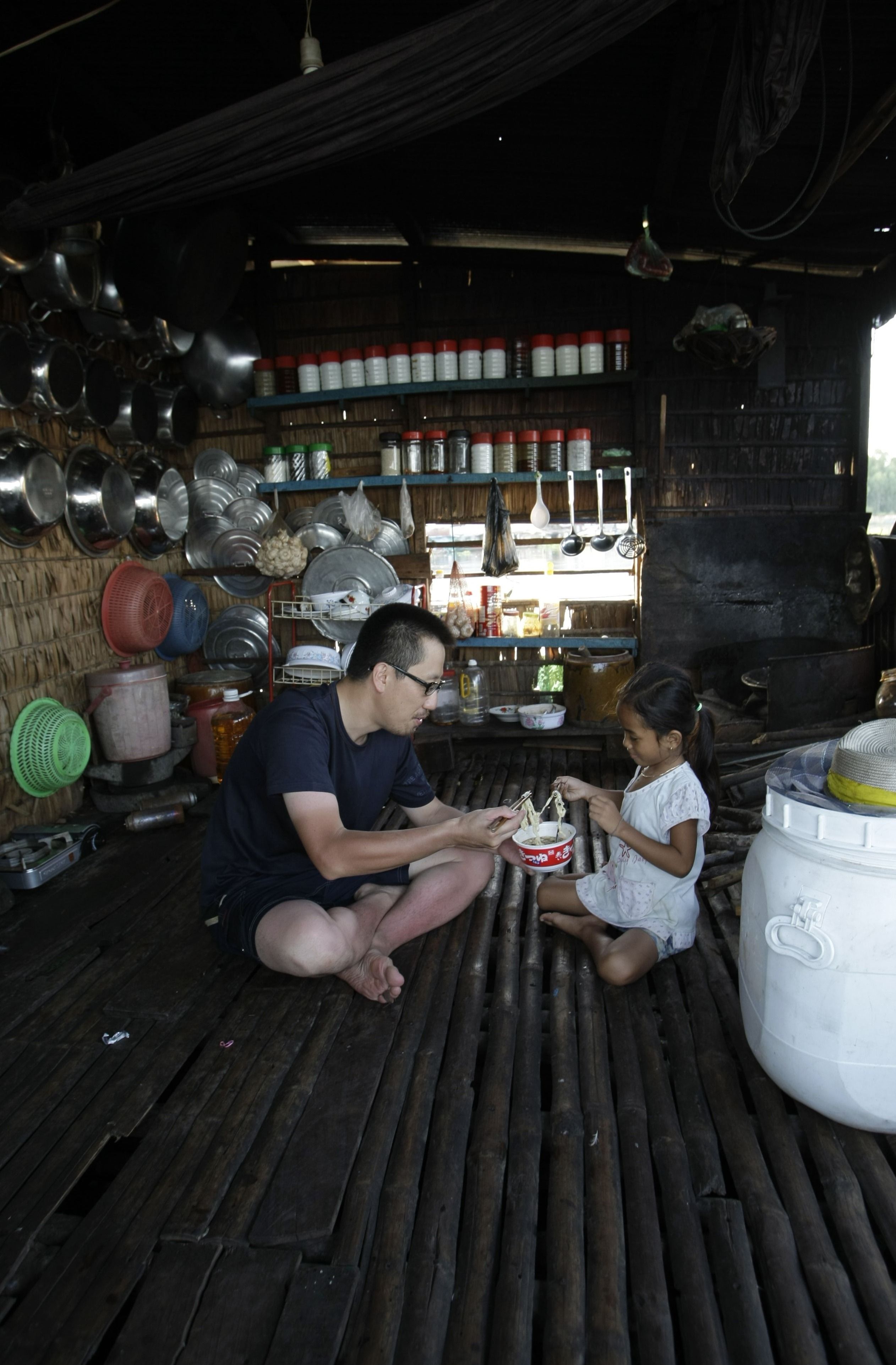 カンボジアの水上集落でカップうどんを分け合う筆者と居候先の娘さん