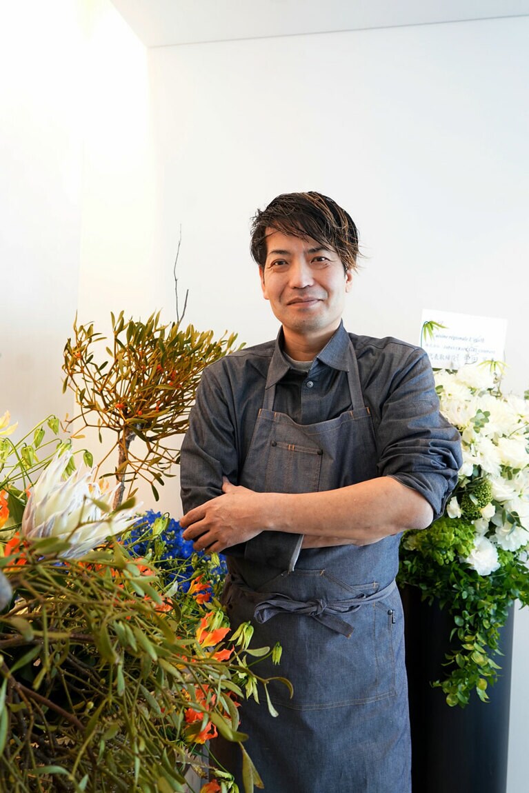 オープン祝いの花に囲まれる谷口英司オーナーシェフ。エントランスからロビーラウンジまで、日本各地から贈られた花やお酒で溢れていた。