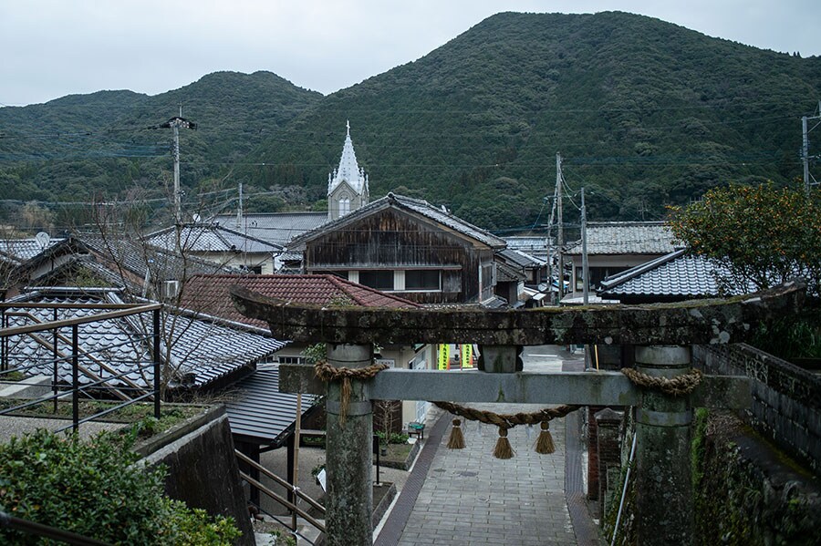 﨑津諏訪神社の鳥居の向こうに見えるのは、集落と﨑津教会。異なる宗教が共存し続けた﨑津らしい風景。
