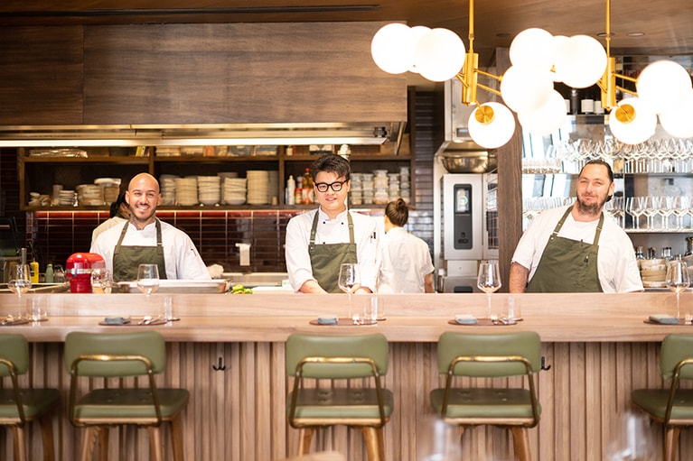 2階「THE RESTAURANT」のオープンキッチンに立つ厨房チーム。 マスターシェフのサイモン・エスコバルさん(左)。ス―シェフのリース・ラングツリーさん(左)。コミシェフのエドワード・グエンさん(中央)。