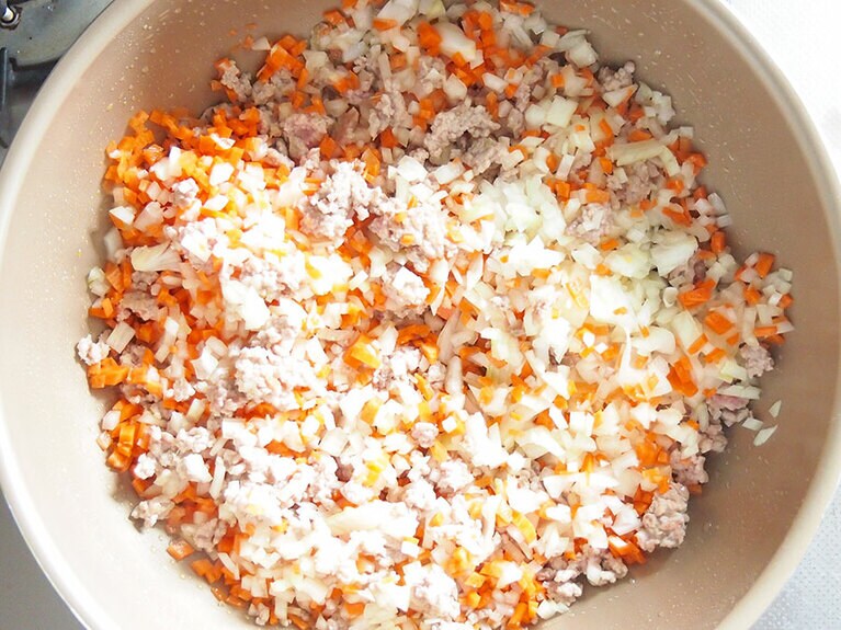 (6) 豚肉の赤みがなくなってきたら、(4)の玉ねぎ、人参を入れて炒めます。