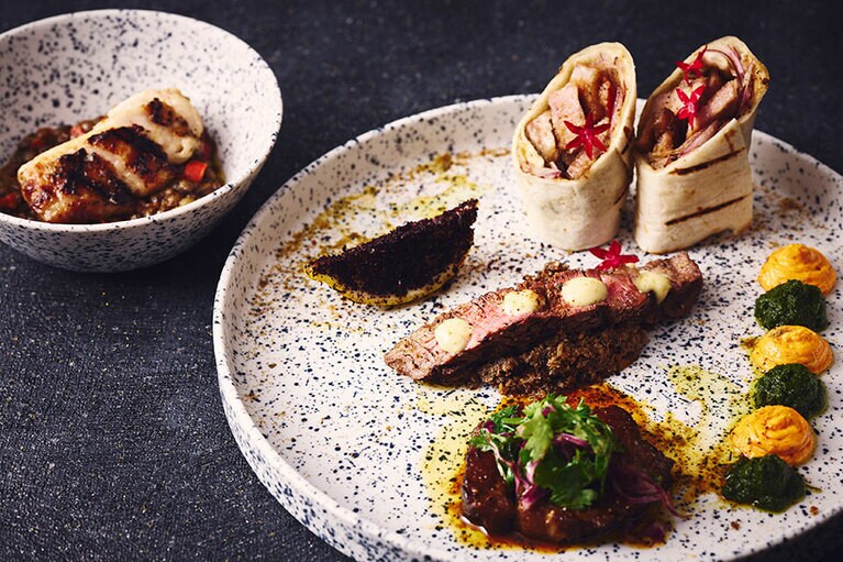 「チャコールBBQプレート」のイメージ。添えられた2種類のソース（ペッパーサルモレッホ　チャラモーラケイジャン）で味変を楽しむのもおすすめ。