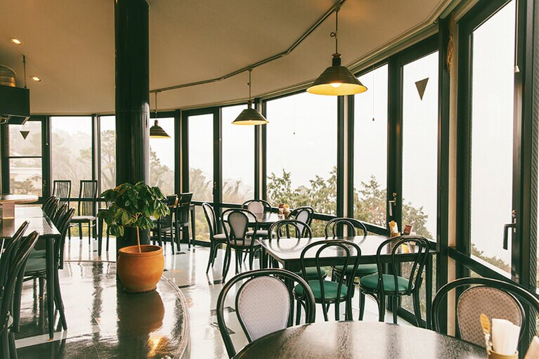 江之浦ならではの、柑橘樹が茂った急斜面に建ち、丸くせり出したテーブル席からの景色が贅沢。高台から水平線を眺めながら優雅な時間を過ごすことができる。