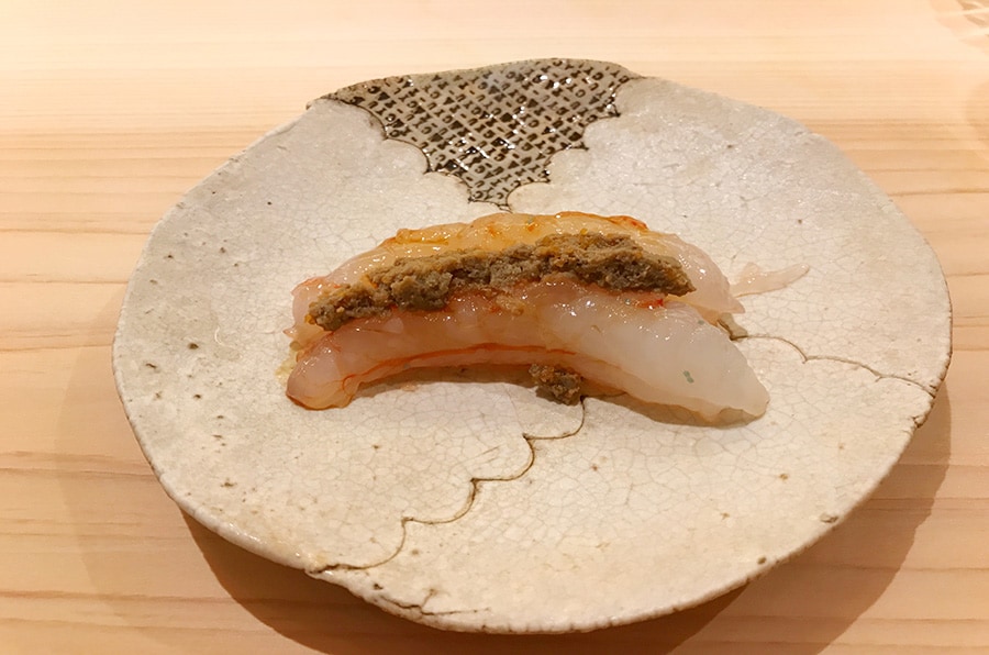 北海道増毛町のボタン海老の上に載っているのは、焼いた殻を混ぜた味噌。殻の食感と香ばしさがアクセントとなっている。