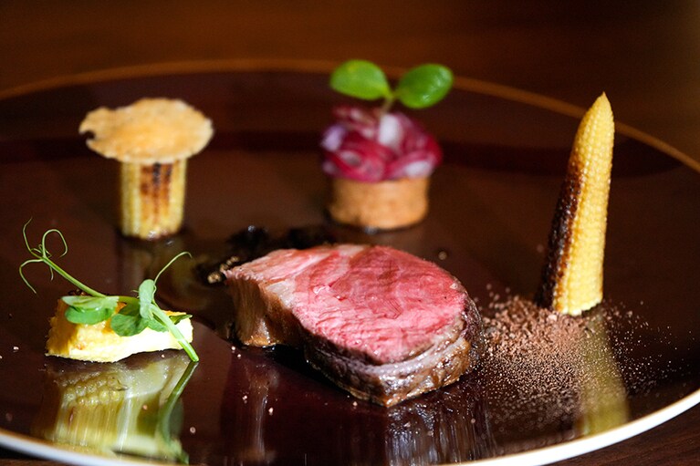 肉料理：ビゴール豚、ブーダンノワール、ヤングコーン、ラディッシュ、チーズの煎餅とうもろこしの甘さとカカオリテ、自家製りんごビネガーとプルーンのソース。