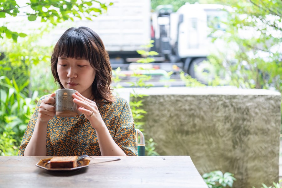 涼しい風が吹き抜けるテラス席でほっと一息つきながら美味しい時間を楽しむサヤカさん。