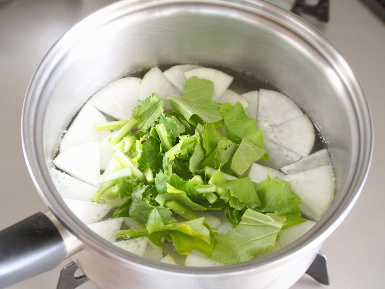 具材が柔らかくなったら、蕪の葉を入れる。