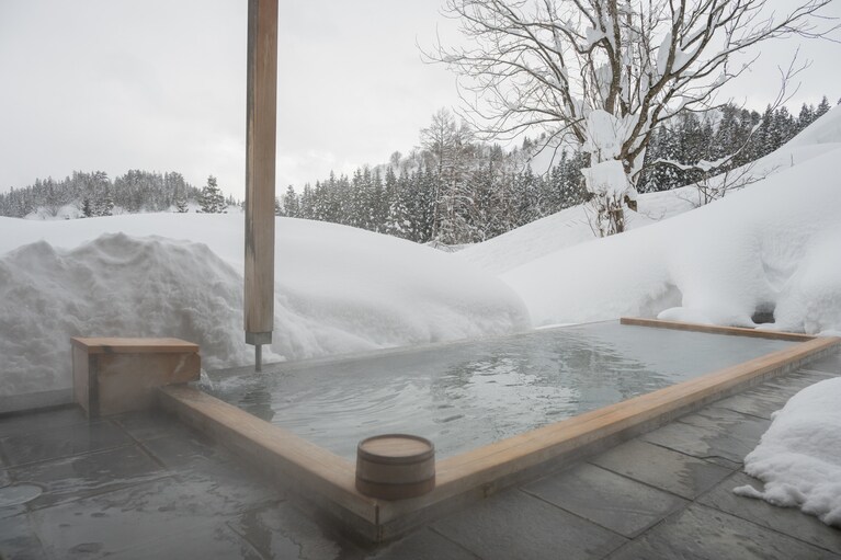 源泉は大沢山温泉。宿に着いたら、まずは温泉に浸かり、冷えた体を温め、銀世界に浸りたいもの。北越の山々を一望できるはずの「里山十帖」の露天風呂ですが、今年は大雪で一面に覆われた雪に圧倒されます。