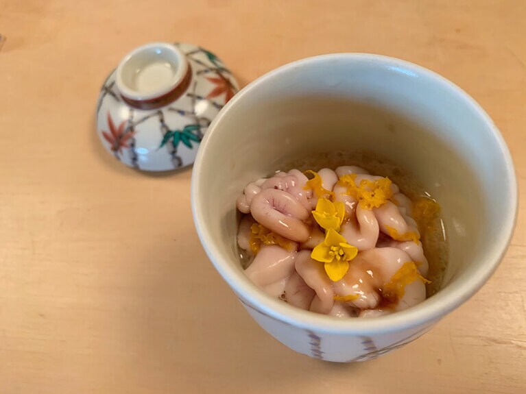 蓋付きの器には、季節の香箱ガニと平飼いの卵を使った茶碗蒸し。マダラの白子と木柚、菜の花がトッピングされていて華やかだ。