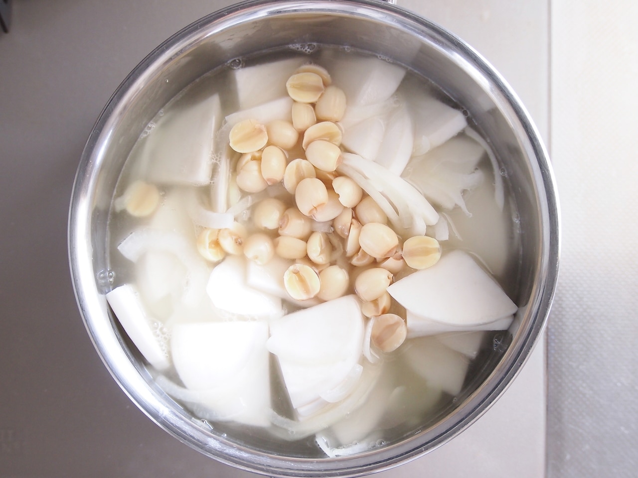 玉ねぎがしんなりしてきたら、カブ、茹でた蓮の実、鶏がらスープの素、ヒタヒタの量の水を入れて加熱する。