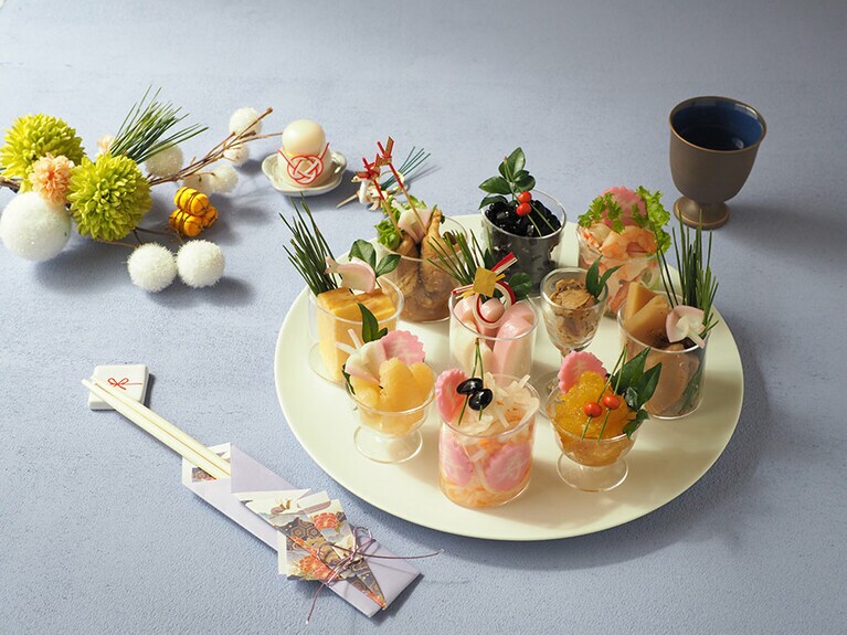 「リモートおせち」。中央より時計回りで、御蒲鉾 赤板、味付け帆立、海鮮サラダ、たけのこ煮、つぶつぶ栗きんとん、寿なると 赤、なます漬、ふぐ蒲、厚焼きたまご、豚の旨煮、黒豆。