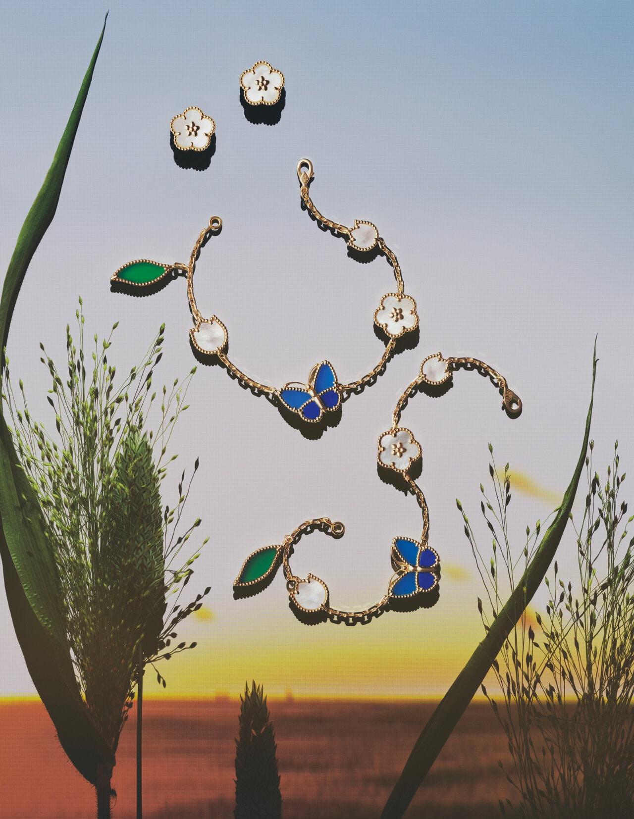 ≪上≫「ラッキー スプリング イヤリング、プラムブロッサム」（YG×ホワイトMOP）852,500円、≪中・下≫「ラッキー スプリング パピヨン ブレスレット、5モチーフ」（YG×ラピスラズリ×ブルー＆グリーンアゲート×ホワイトMOP）各1,082,400円／ヴァン クリーフ＆アーペル（ヴァン クリーフ＆アーペル ル デスク）