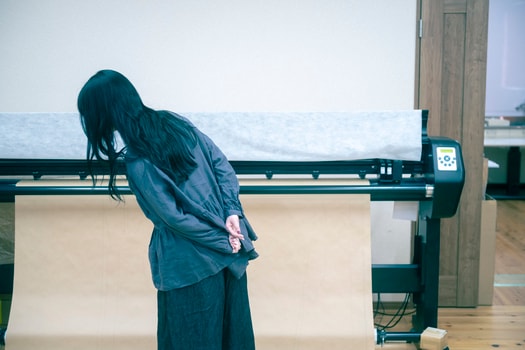 ネストローブ徳島工場を訪れた山田さん。服が仕立てられる過程に、山田さんも釘付け。リネン天然染めギャザーブラウス（C･GREY） 30,800円、リネンデニムワイドジーン（BLACK） 33,000円／ネストローブ