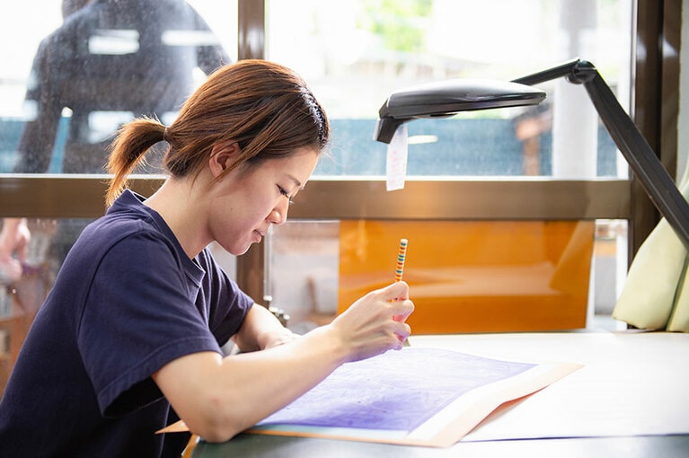 自然光が入る明るい工房で仕事に集中する職人さん。