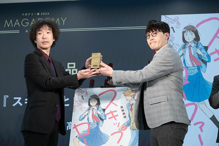 左から：作者の高松さんの代理でトロフィーを受け取る、講談社「アフタヌーン」編集部の宮崎孝士さんと菊田さん。