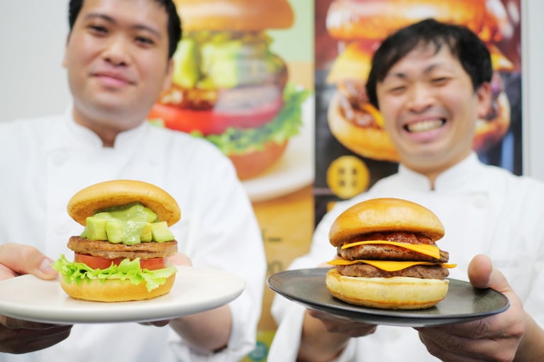 「アボカドバーガー」開発担当の渡部拓巳さんと「『モスの匠味』黒毛和牛のダブルチーズバーガー」開発担当の上田洋輔さんがそれぞれ自信作を手に声を揃えて「どちらもモスの自信作です。ぜひ『いただきモス！』して下さいね」と熱くメッセージ。