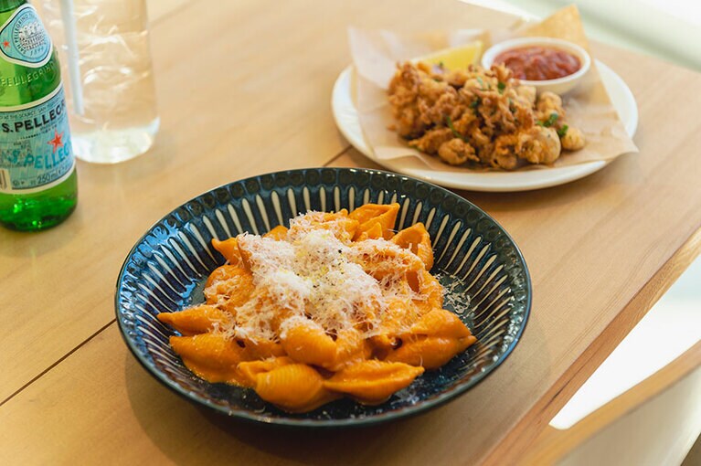 手前から、トマトやタマネギベースのピリ辛味のウォッカソース コンキリエ W12,000、小ぶりのイカを揚げた料理のフライド カラマリ W7,000。今後スペシャルメニューとしてピザが登場する予定。