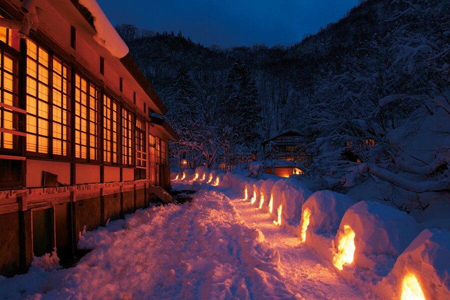 【ランプの宿 青荷温泉】窓から漏れる灯りが雪に反射し、独特の景色を作る冬の夕暮れ。素朴な風情が郷愁を誘う。