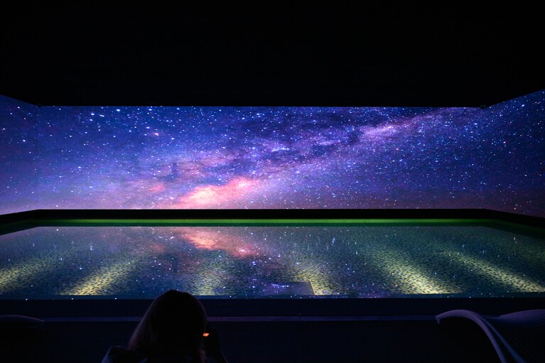 まるで宇宙にいるかのような、無数の星が輝く映像が壁一面に広がり、静かに水面を照らします。幻想的な演出に思わずうっとり。