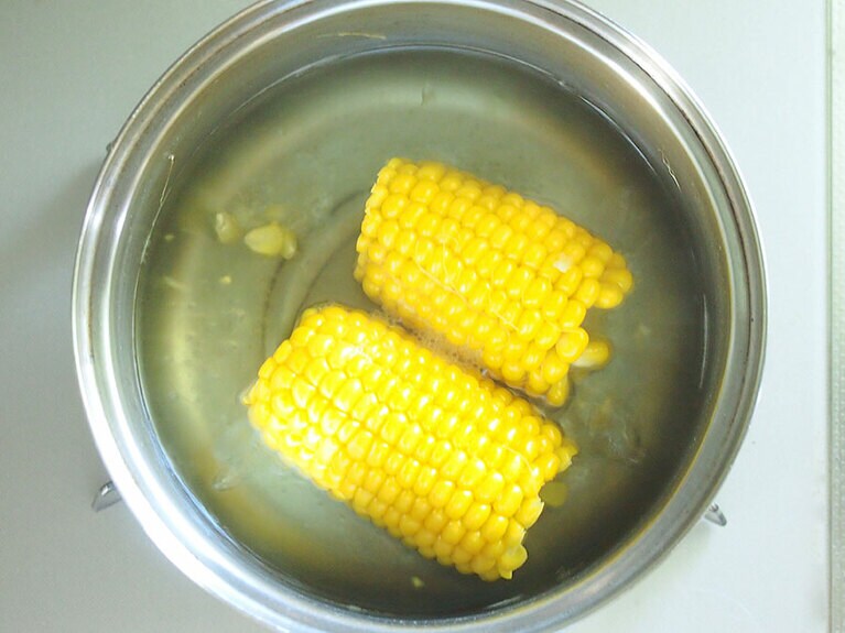 (3) トウモロコシは皮をむき、半分に切ったら、沸騰した湯に入れて煮ます。