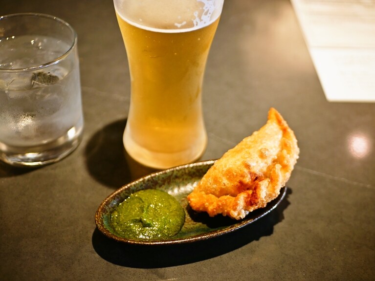 アルゼンチンのミートパイ、エンパナーダ（7ドル）でビールを。左脇のチミチュリソースが素晴らしき付け合わせ。
