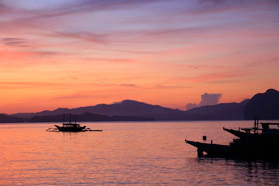 リゾート島から眺める夕焼けは筆舌に尽くしがたい美しさ。バンカーボート（船体の左右に翼を広げたように揺れを防ぐ浮きが伸びている船）のシルエットがフィリピンらしさを添えている。
