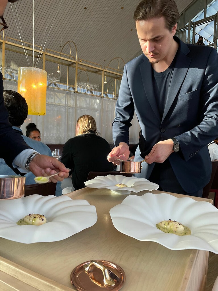 テーブル横で温かい魚介風味のスープを回しかけて提供される。