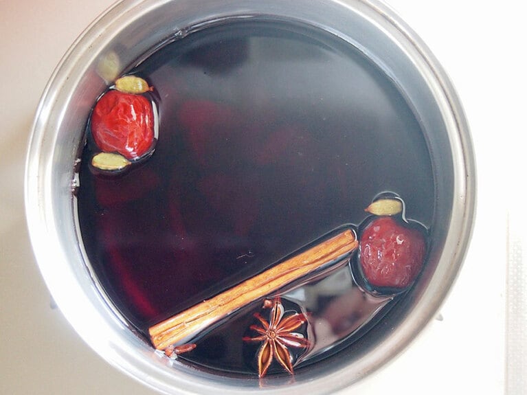 (2) 鍋に赤ワイン、水、(1)のなつめと生姜、［A］のスパイスを入れて加熱します。