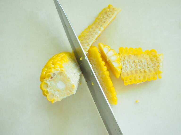 (4) 10分ほど茹でてトウモロコシに火が入ったら、包丁で軸から実をそぎ取ります。