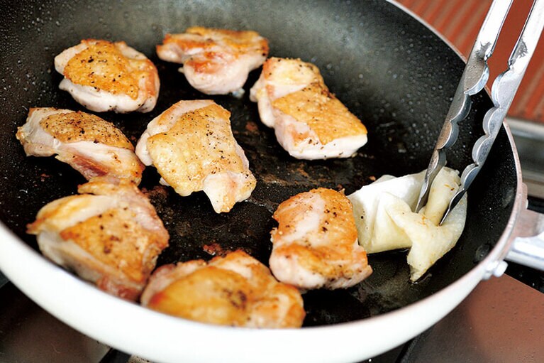 鶏肉の皮を下にして入れたら、鍋を動かさず、じっとがまん。このきつね色の焼きめがおいしさに直結。鶏肉から脂が出たらふいておきます。