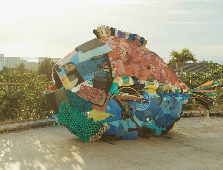 【淀川テクニック《やんばるオオゴミウオ》】その土地のゴミを用いて作品制作を行うアーティスト、淀川テクニック。やんばるで地元の人々とともに集めた漂着ゴミを使用して作られた《やんばるオオゴミウオ》は、「オキナワ マリオットリゾート＆スパ」に展示された。