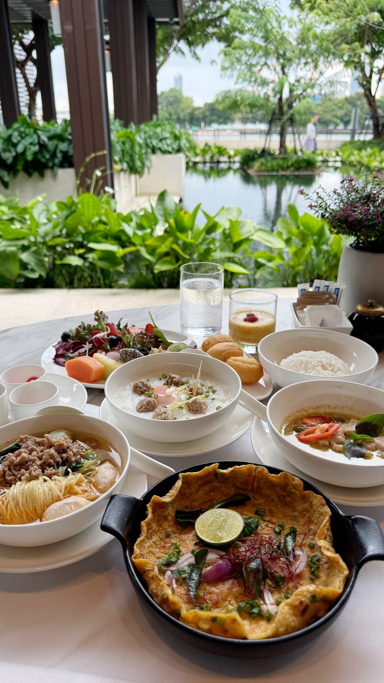 朝食で味わえるタイ料理の数々。手前はタイ風オムレツ、左は豚ひき肉と豚肉団子入りのトムヤム味のスープ麺。中央は温泉卵と豚ひき肉入りのタイ粥、右は鶏肉のグリーンカレー。