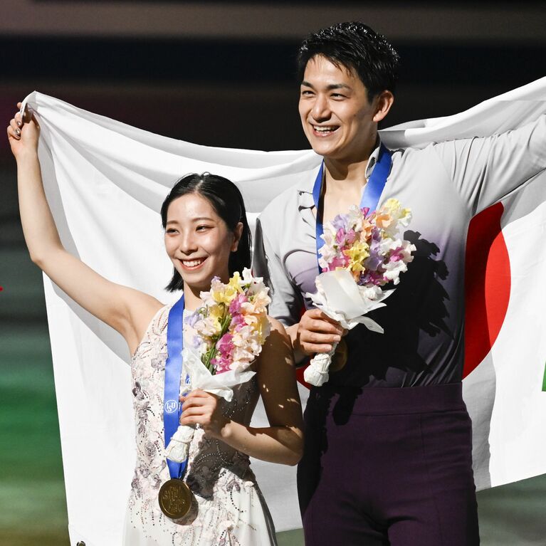 2人で日の丸を掲げるりくりゅう（三浦璃来、木原龍一）©JMPA