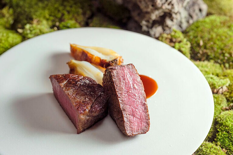 中川一辺陶の炭台で焼く近江牛。ゆっくりとコンフィにした京都の新玉ネギを添える。撮影＝橋本篤
