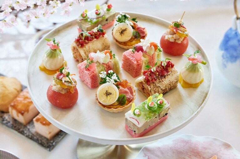 「桜アフタヌーンティー」より、旬の食材を使ったセイボリー（3種）＆フィンガーサンドウィッチ（3種）が華やかに盛り付けられたプレートのイメージ。このほかグラスセイボリー1種、スイーツ8種、スコーン2種、コーヒーまたは紅茶付き。