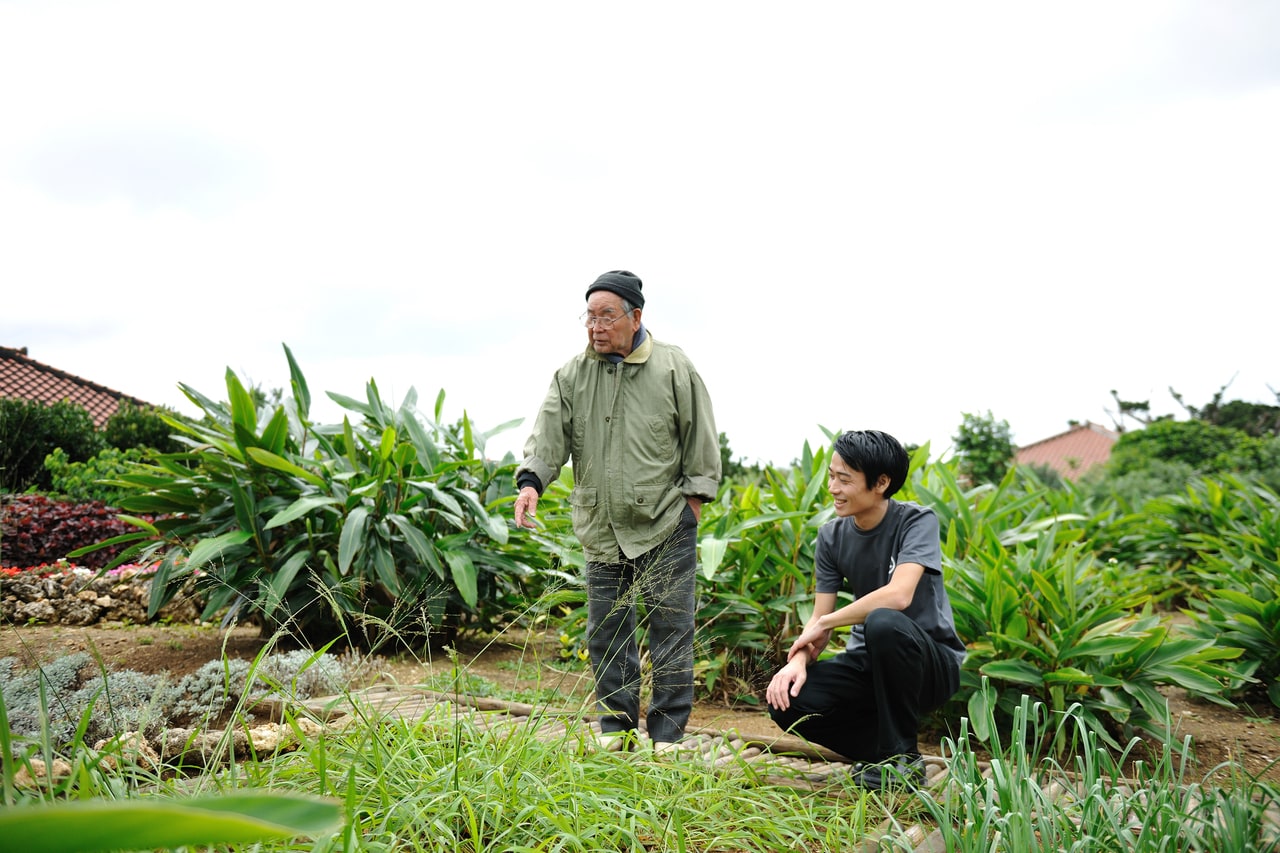 島の長老・前本隆一さんの教えを受ける、プロジェクトリーダーの小山隼人さん。