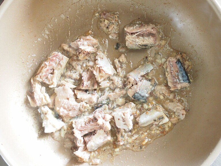 (2) フライパンに(1)のにんにく、オリーブオイルを入れて火にかけます。にんにくがきつね色になってきたら鯖の水煮缶を入れます。※缶の汁も使用します。一緒にフライパンへ入れましょう。