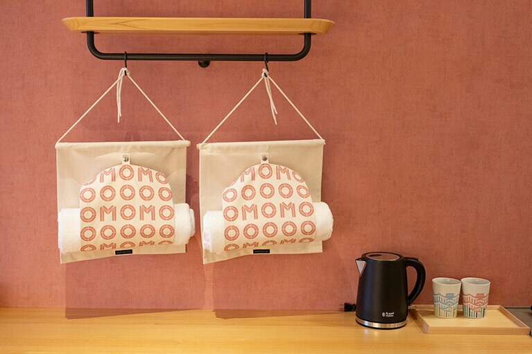 熊本城モチーフのオリジナルカップや電気ケトル、ドライヤーなどを完備。歯ブラシやヘアブラシ、ボディタオルなどはフリーで、フロント横に用意あり。ルームウェア（200円・税込）やスキンケアブランド「OSAJI」のアメニティセット（360円）もあるので、荷物をたくさん持っていかなくてOK。