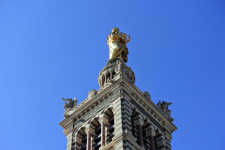 マルセイユの守護聖人、聖母マリアが丘の上の聖堂から人々と港を見守っています。