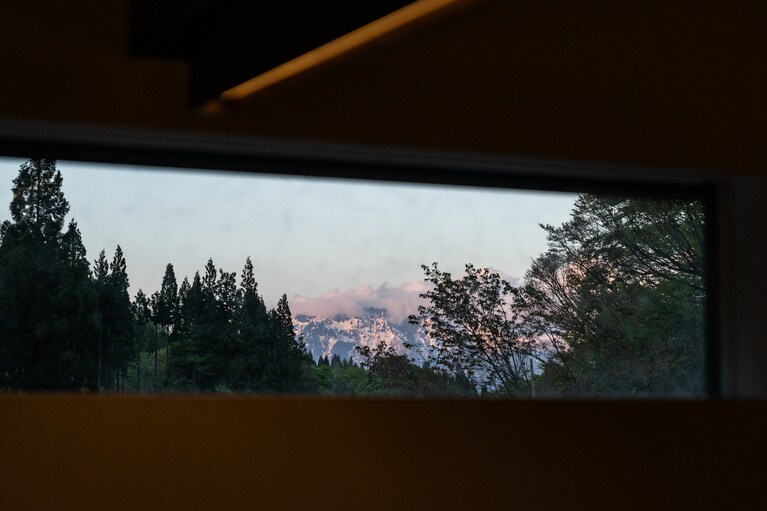 窓の向こうには雪を残した山が。うっすら紅く染まるころに夕食がスタート。