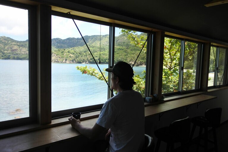 シェアハウスの共同ラウンジからは扇浦を一望します。この人が海さん。