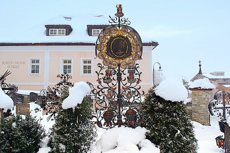 歌詞を書いたヨーゼフ・モール神父の墓。後ろに見えるピンクの建物が神父の創立した学校だ。