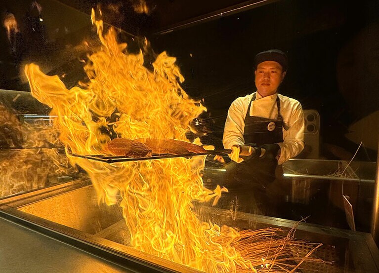 迫力満点の藁焼き。キッチンは耐熱ガラスの向こうなのでご安心ください。