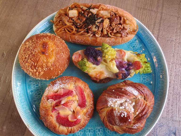 人気のパン。上から時計回りに「焼きそばパン」320円、「自家製ベシャメル、チーズと旬素材のタルティーヌ」300円、「スウェーデン直伝レシピのシナモンロール」260円、「季節の焼きフルーツデニッシュ」300円、「自家製カレーの焼きカレーパン」250円。