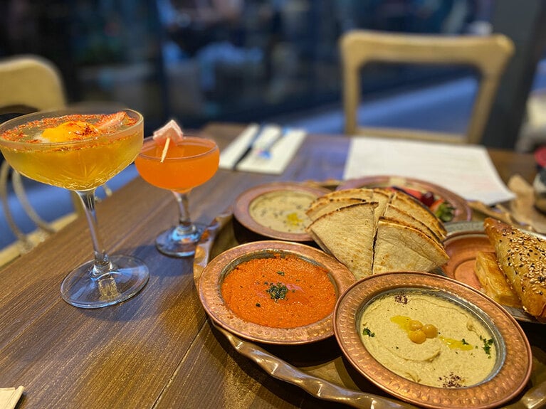 写真左から時計周りに、「ターキッシュサフランマンゴー シャーベット&プロセッコ(Turkish Saffron Mango Sorbet & Prosecco)」12ドル、「ハーレムドリームス(Harem Dreams)」14ドル、フムスやピタなどが盛られた「メゼプラッター(Meze Platter)」32ドル。