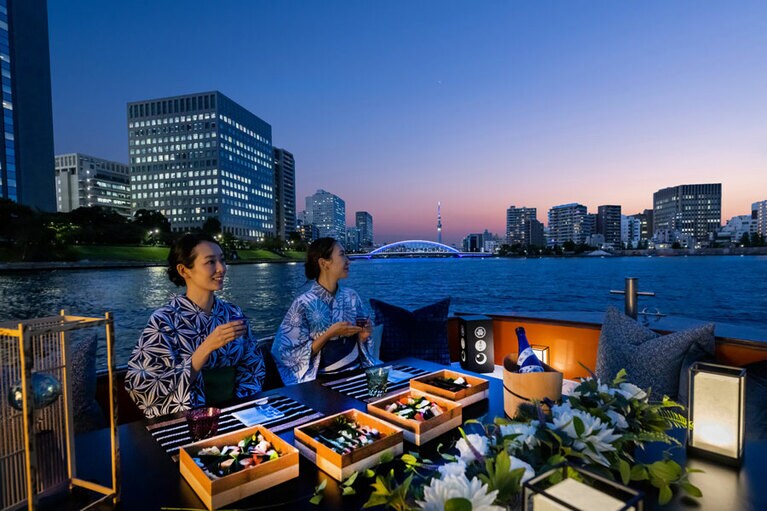 ブルーにライトアップされている橋は、国指定・重要文化財の永代橋。旬の魚や野菜、押し寿司や甘味などで仕立てた四段重を、夏酒とともに賞味する。