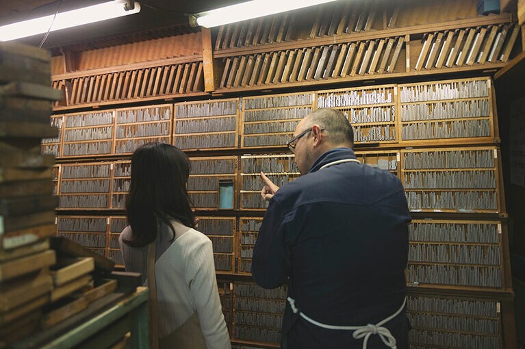 金属活字の説明をする佐々木さんと影山さん。