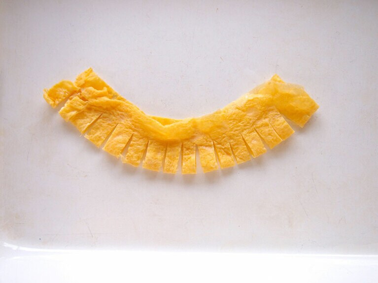 (4) 卵焼きを縦長に3等分に切り、半分に畳んだら、包丁で切り込みを入れます。