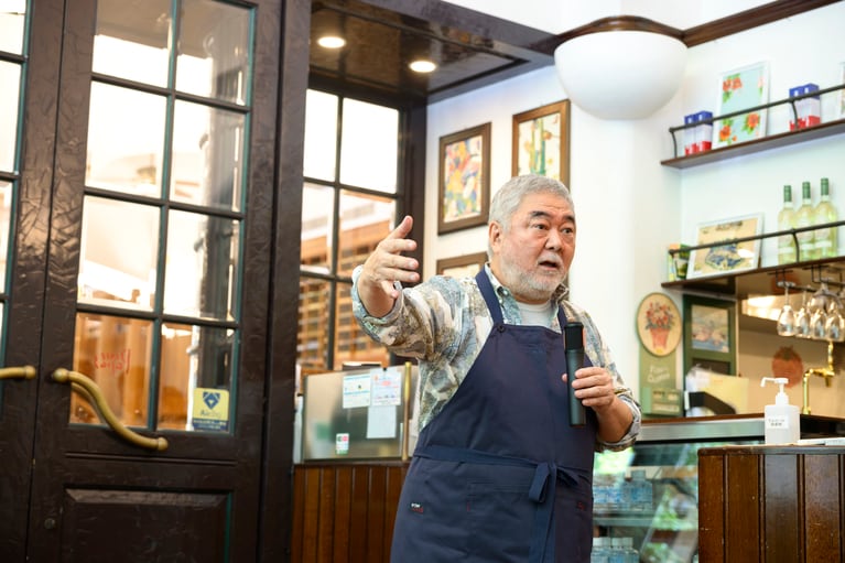 記者に向かって身振り手振りで説明する三國シェフ