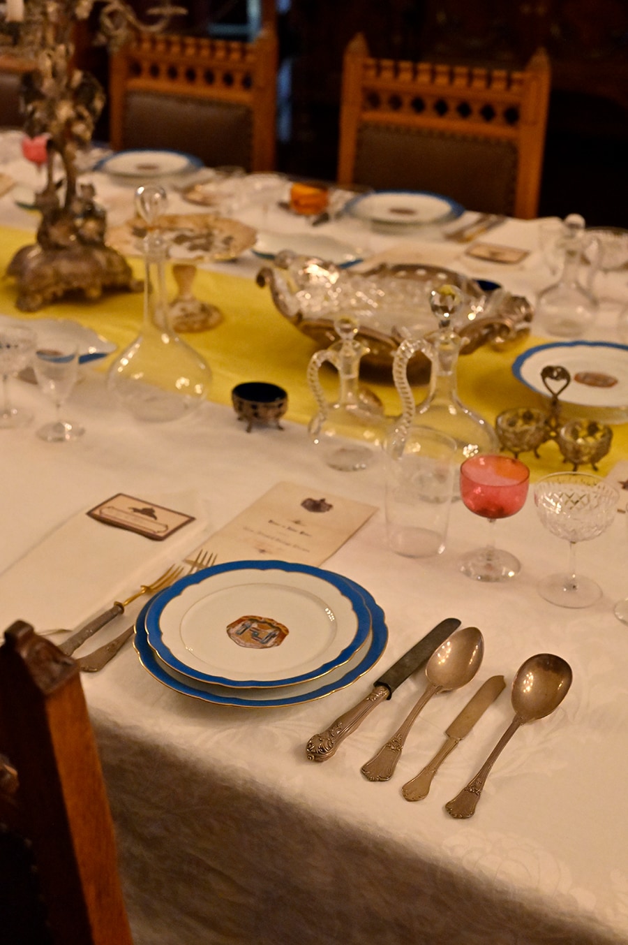 正餐の間のダイニングテーブル。皿やグラスには王室の紋章や王冠がデザインされている。